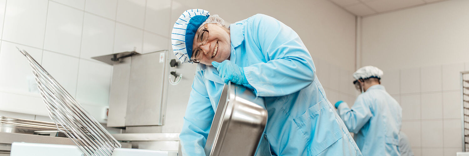 Das Bild zeigt eine Mitarbeiterin beim Waschen einer Schüssel.