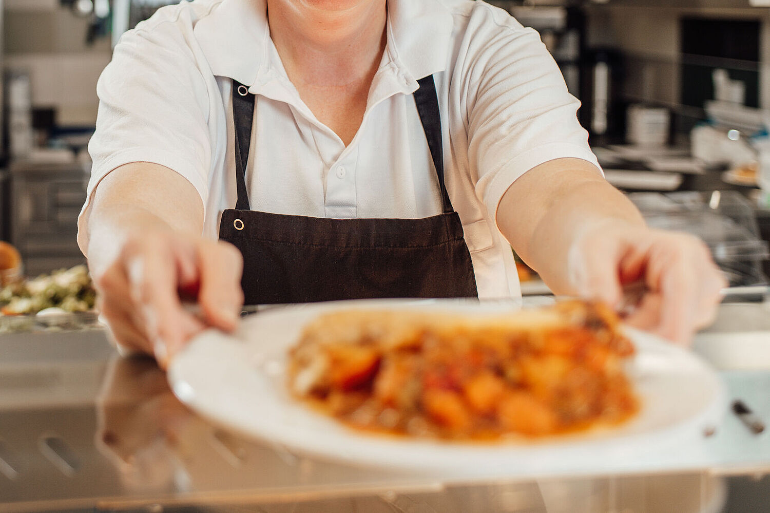 Das Bild zeigt eine Dame der Hauswirtschaft mit einem Teller in der Hand.